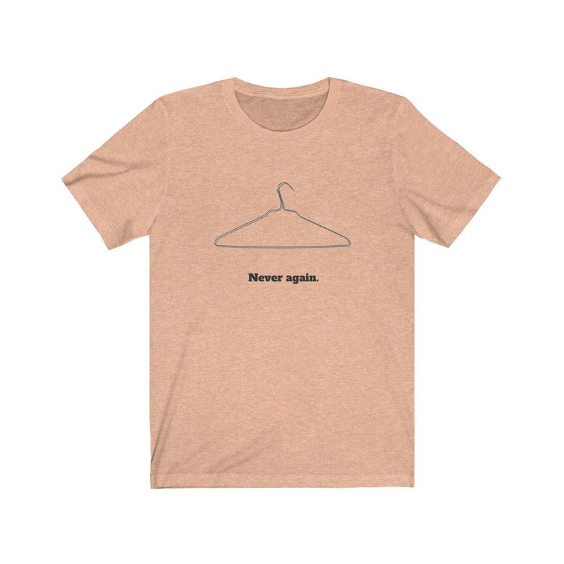 May include: A light peach colored t-shirt with a black wire hanger graphic and the text "Never again." printed below the hanger.
