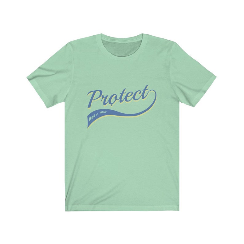 May include: A light green t-shirt with a blue and yellow graphic that says "Protect Roe v. Wade" in a retro-style font.