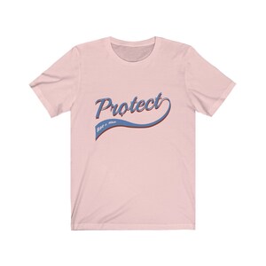 May include: Pink t-shirt with a blue and red "Protect Roe v. Wade" graphic.