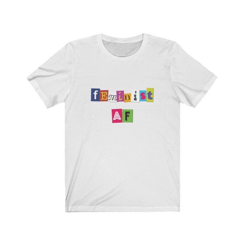 May include: White t-shirt with the text "feminist AF" in colorful, cut-out letters.