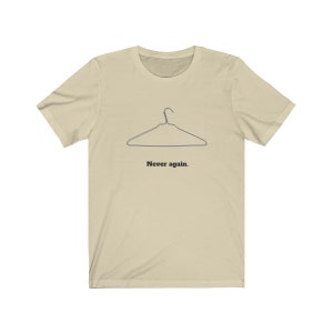 May include: A beige t-shirt with a black wire hanger graphic and the text "Never again."