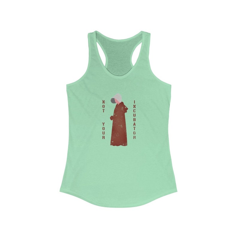 May include: A green tank top with a distressed red graphic of a person wearing a brown robe and a white mask. The text "NOT YOUR INCUBATOR" is printed vertically on either side of the graphic.