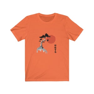 Puede incluir: Camiseta naranja de manga corta con una ilustraci&oacute;n en blanco y negro de un &aacute;rbol en una roca con un sol rojo detr&aacute;s. El texto japon&eacute;s "呼吸する" est&aacute; impreso en el lado derecho de la camiseta.