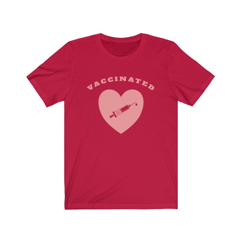 May include: Red short-sleeved t-shirt with the text "VACCINATED" in pink letters and a pink heart with a pink syringe inside.