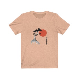 Puede incluir: Una camiseta de color melocot&oacute;n jaspeado con una ilustraci&oacute;n en blanco y negro de un pino japon&eacute;s y un sol rojo. El texto "呼吸する" est&aacute; impreso en negro debajo de la imagen.