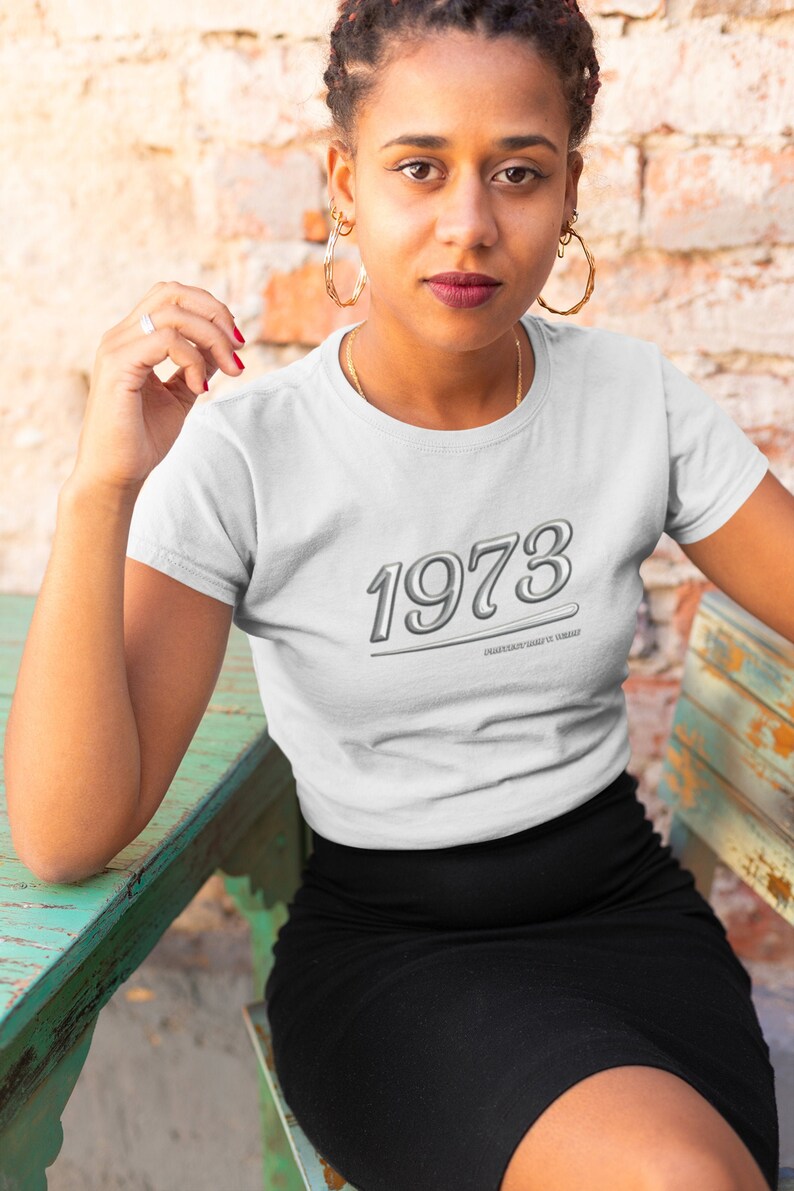 May include: White t-shirt with a silver 1973 graphic and the text "Whatever your vibe is vibe it".