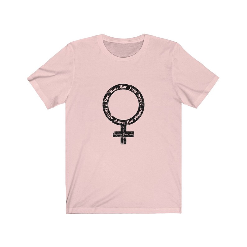 May include: Pink t-shirt with a black and white graphic of the female gender symbol. The graphic has the text "Row, Row, Row your boat gently down the stream" around the symbol.
