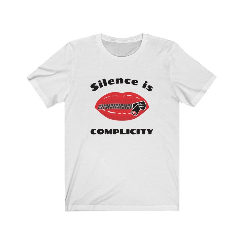 Puede incluir: Camiseta blanca con una boca roja con una cremallera cerrada sobre ella. El texto "Silence is Complicity" est&aacute; impreso debajo de la boca.
