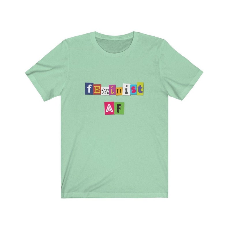 May include: A light green t-shirt with the text "feminist AF" in colorful, cut-out letters.