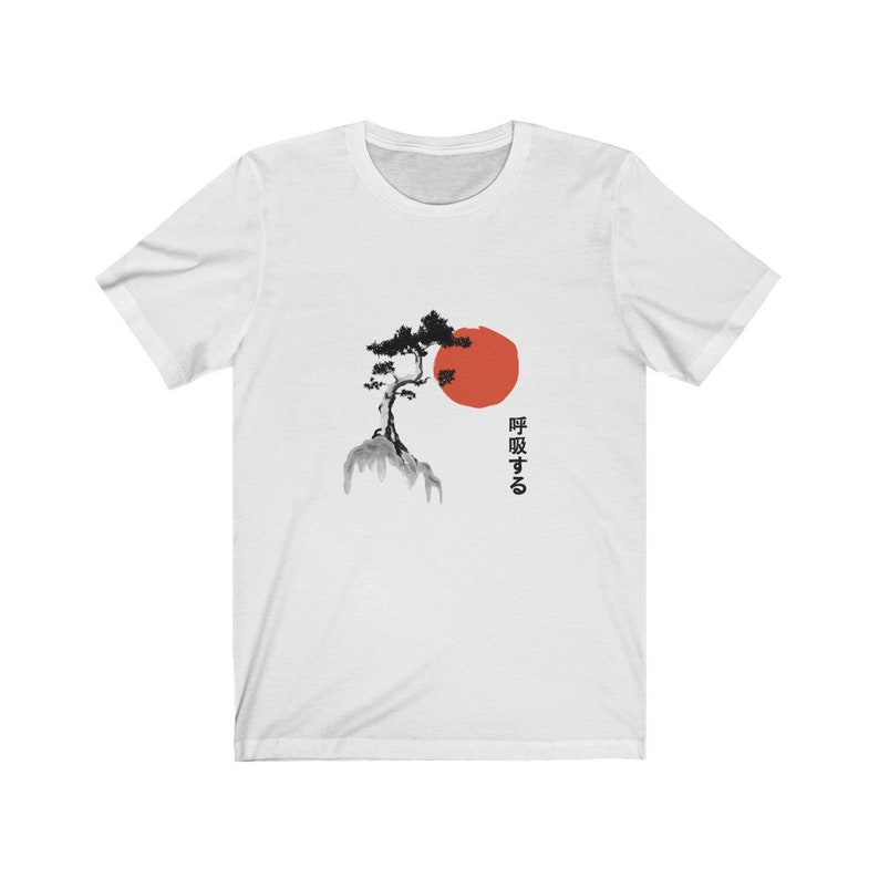 Puede incluir: Camiseta blanca con una ilustraci&oacute;n en blanco y negro de un &aacute;rbol en una monta&ntilde;a con un sol rojo detr&aacute;s. El texto japon&eacute;s "呼吸する" est&aacute; impreso debajo de la imagen.