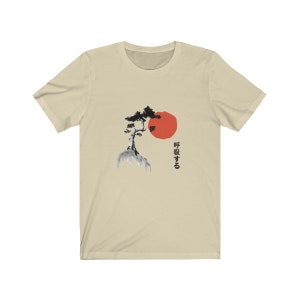 Puede incluir: Una camiseta beige con una ilustraci&oacute;n en blanco y negro de un &aacute;rbol en una roca con un sol rojo detr&aacute;s. El texto japon&eacute;s "呼吸する" est&aacute; impreso en el lado derecho de la camiseta.