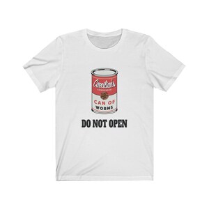 Puede incluir: Camiseta blanca con un gr&aacute;fico de una lata roja etiquetada "Caecilians Condensed Can of Worms" con el texto "DO NOT OPEN" debajo.