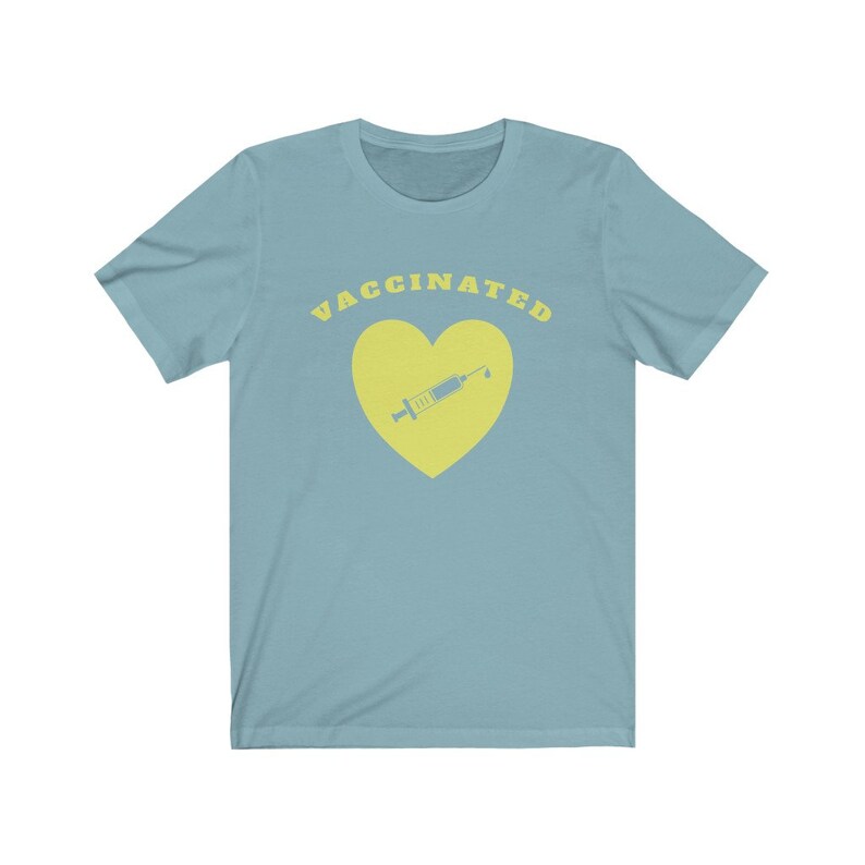 May include: A light blue t-shirt with the text "VACCINATED" in yellow letters. A yellow heart with a yellow syringe inside is below the text.