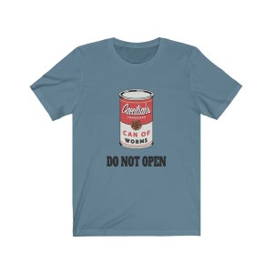 Puede incluir: Una camiseta azul con un gr&aacute;fico de una lata roja etiquetada "Caecilian's Condensed Can of Worms" con el texto "Do Not Open" debajo.