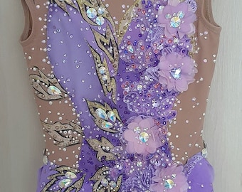 May include: A purple and brown leotard with a floral design and rhinestones. The leotard has a scalloped bottom and a sheer overlay.