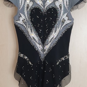 May include: A black and grey figure skating costume with a heart-shaped design and rhinestones.