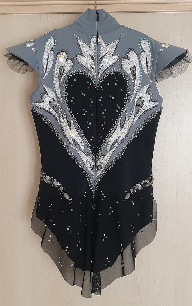 May include: A black and grey figure skating costume with a heart-shaped design and rhinestones.