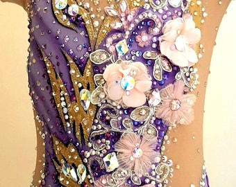 Pode incluir: Um collant sem mangas em tecido degradê roxo com aplicações douradas em forma de folha, cristais transparentes e flores de tecido rosa pálido. O corpete inclui painéis de malha nude transparente no decote e nas laterais com strass.