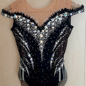 May include: Black leotard with a sheer mesh overlay and a decorative design of rhinestones. The leotard has short sleeves and a scoop neck.