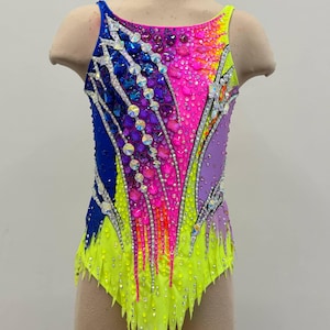 May include: A colourful leotard for gymnastics or dance, with a gradient of colours from blue to yellow, with pink and purple accents. The sleeveless garment is embellished with rhinestones and crystals. It has a high neckline and a cut-out leg design.