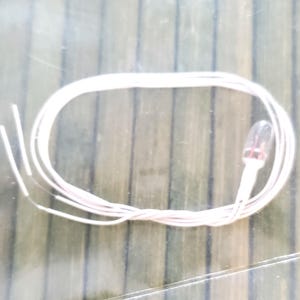 May include: A white wire with a small clear light bulb at the end. The wire is coiled up and ready to be used.