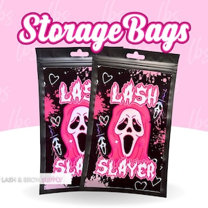 May include: Two black zippered storage bags with a pink and black graphic design. The graphic features a pink ghost with a scream face and the text "LASH SLAYER".