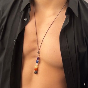 May include: A black cord necklace with a pendant featuring seven colorful gemstones in a rainbow pattern. The pendant is made of amethyst, lapis lazuli, rose quartz, carnelian, citrine, tiger's eye, and black obsidian.