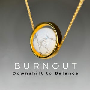Puede incluir: Collar dorado con colgante. El colgante tiene una piedra blanca con vetas grises, engastada en un bisel dorado. El texto "BURNOUT" y "Downshift to Balance" están debajo del colgante.