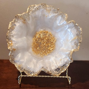 May include: White resin flower-shaped dish with gold leaf accents on a gold metal stand.