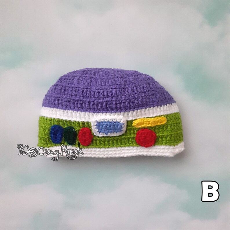 May include: A crocheted hat in the style of Buzz Lightyear's helmet. The hat features a purple top, green and white trim, and colorful accents including blue, red, and yellow details. The hat is handmade.