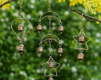 May include: Three hanging wind chimes made of gold-toned metal wire. The left chime features a heart shape, the centre chime has two crescent moons and a star, and the right chime is star-shaped. Each piece includes small, rustic, weathered bells.