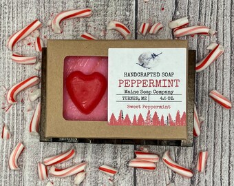 May include: A bar of handmade peppermint soap in a brown box with a white label. The label says "HANDCRAFTED SOAP PEPPERMINT Maine Soap Company TURNER, ME 4.5 OZ. Sweet Peppermint". The soap is pink and has a red heart shape in the center.
