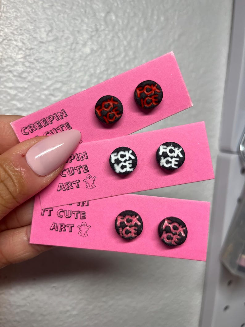 May include: Three pairs of round stud earrings, each black with a contrasting red or white design. The earrings are presented on pink cards, with the text "CREEPIN CUTE ART" printed on them.