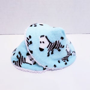 May include: Two blue baby burp cloths with a white trim and a zebra print.