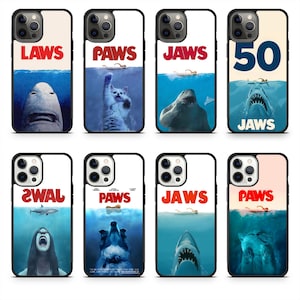 May include: A collection of phone cases featuring designs inspired by the movie "Jaws." The cases display images of sharks, cats, and text like "LAWS," "PAWS," and "JAWS." The cases have a black border and a white background.