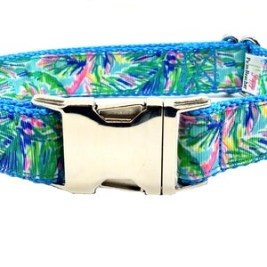 May include: A blue dog collar with a tropical leaf print and a silver buckle. The collar has a silver D-ring and the text "Happy Teacher" is printed on the collar.