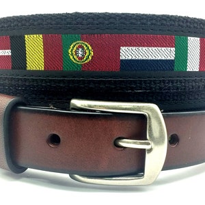 May include: A brown leather belt with a silver buckle. The belt has a black canvas strap with a woven design featuring flags of different countries.