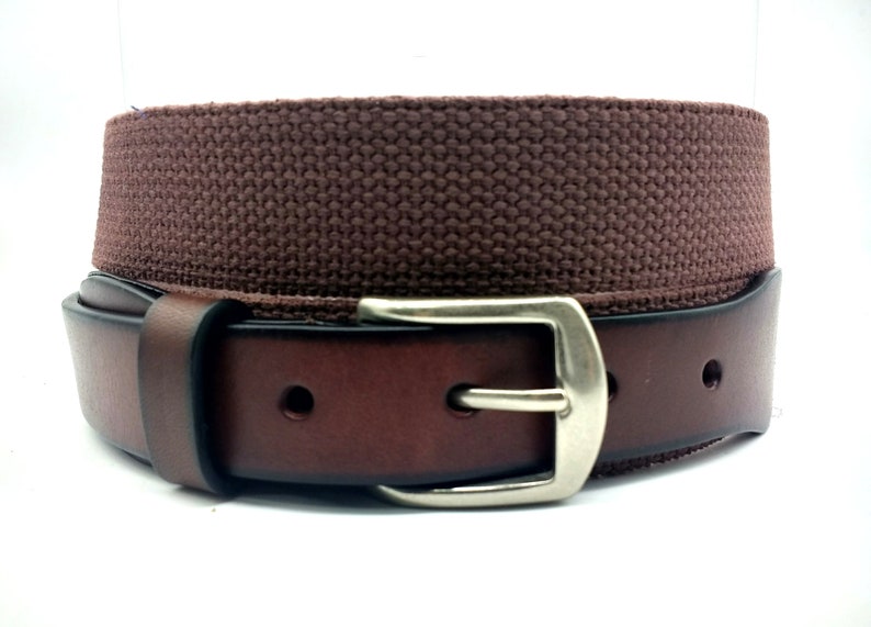 Puede incluir: Un cintur&oacute;n de cuero marr&oacute;n con una correa de lona y una hebilla plateada.