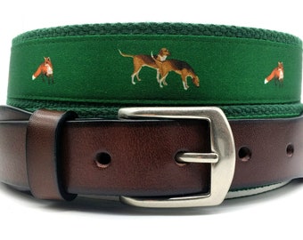 May include: A brown leather belt with a green canvas strap featuring a repeating pattern of foxes and hounds. The buckle is silver.