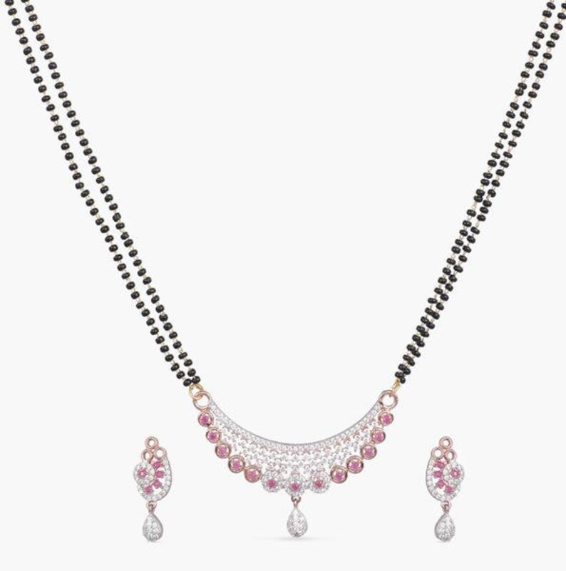 May include: A black beaded necklace with a pendant featuring a crescent-shaped design with pink and white stones. Matching earrings with a similar design are also included.