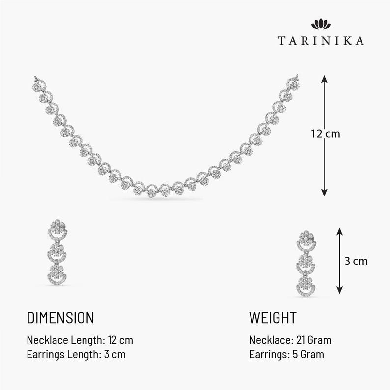 May include: A silver necklace and earrings set with a delicate design of small, round, sparkling stones. The necklace is 12 inches long and the earrings are 3 inches long. The necklace weighs 21 grams and the earrings weigh 5 grams.