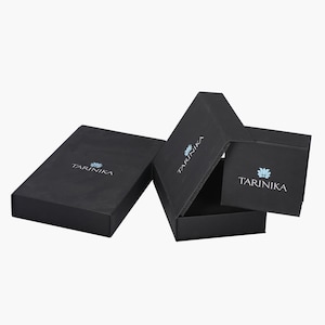 May include: Three black gift boxes with the logo "TARINIKA" printed on each. The logo features a stylized blue flower.