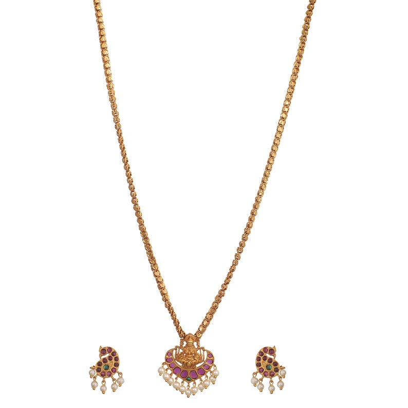 K&ouml;nnte beinhalten: Eine goldene Halskette mit einem Anh&auml;nger, der eine G&ouml;ttin mit rosa und gr&uuml;nen Edelsteinen zeigt. Die Halskette wird mit passenden Ohrringen im gleichen Design geliefert.