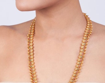 May include: A gold necklace with green and red gemstones. The necklace has a floral design and is made of small, round beads. The necklace is worn by a person with a light complexion.