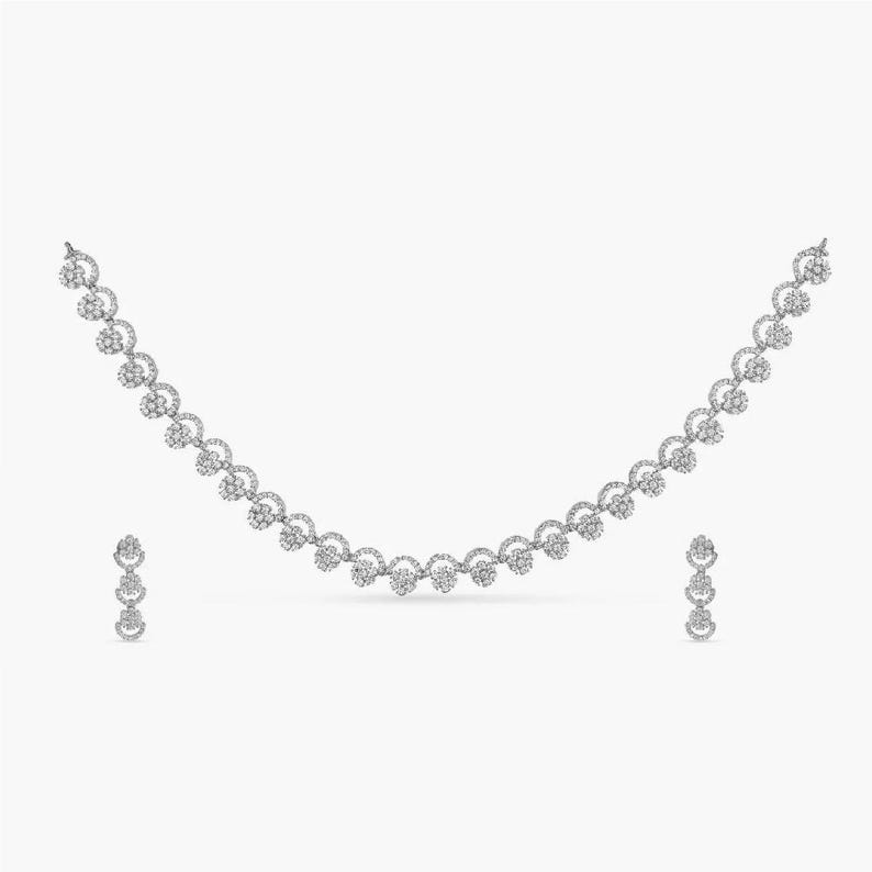 May include: A silver necklace and earrings set with a delicate design of small, round, white stones.