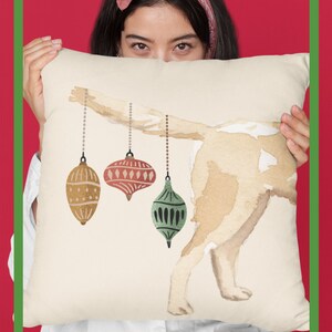 May include: A white throw pillow with a watercolor illustration of a dog with three Christmas ornaments hanging from its tail. The text "FAMILY KEEPSAKE GIFTS FOR DOG LOVERS" is printed below the image. The Creative Pioneer Design for an Inspired Life is printed in the bottom left corner.