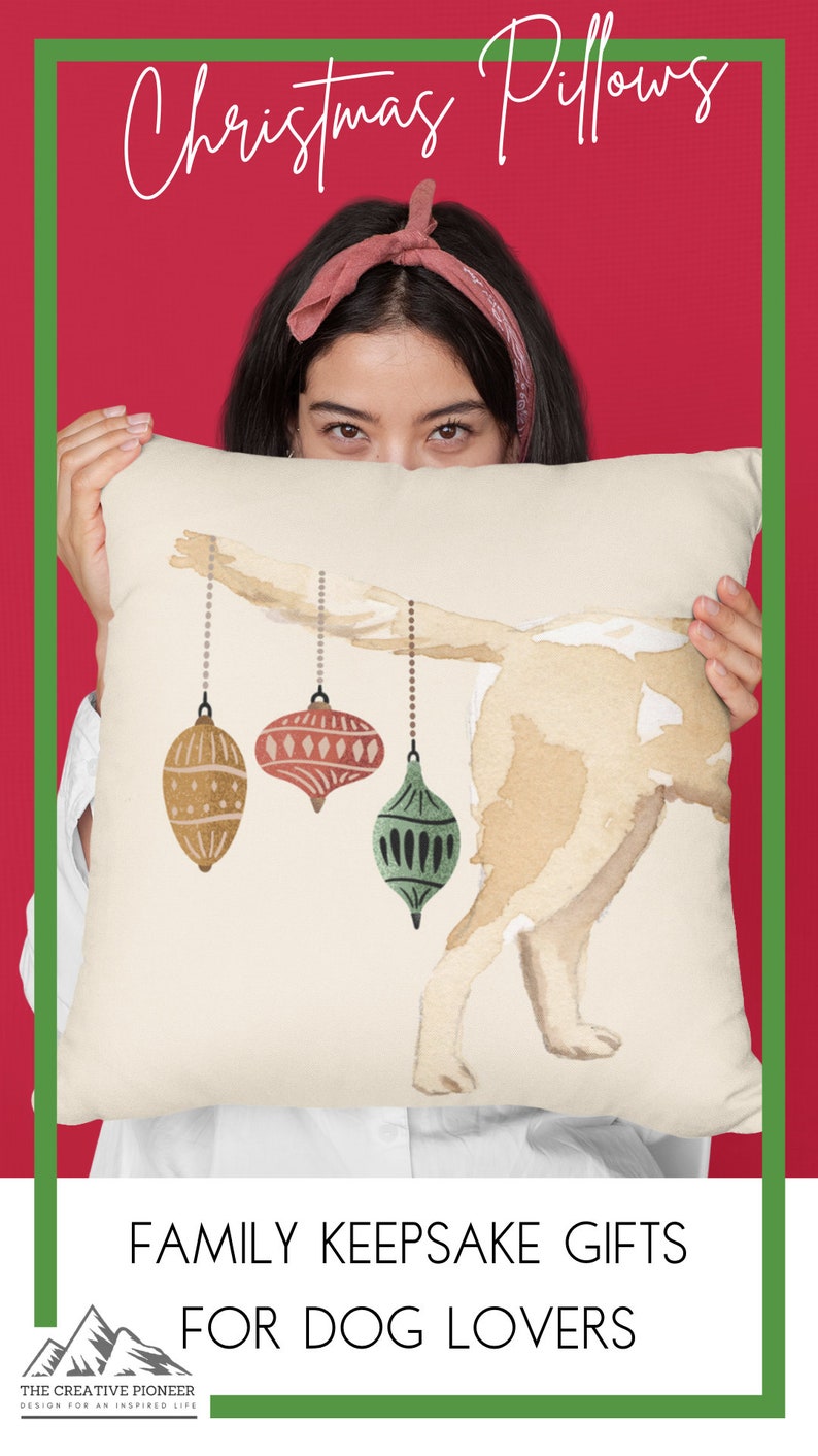 May include: A white throw pillow with a watercolor illustration of a dog with three Christmas ornaments hanging from its tail. The text "FAMILY KEEPSAKE GIFTS FOR DOG LOVERS" is printed below the image. The Creative Pioneer Design for an Inspired Life is printed in the bottom left corner.