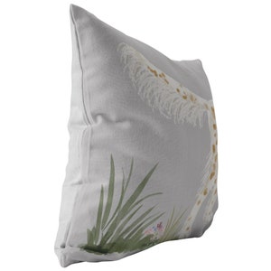 May include: A gray throw pillow with a white and brown giraffe print. The giraffe is surrounded by green leaves and pink flowers.