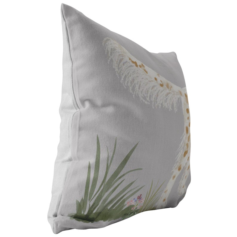 May include: A gray throw pillow with a white and brown giraffe print. The giraffe is surrounded by green leaves and pink flowers.