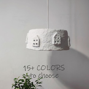 May include: White paper mache pendant light fixture with two small house-shaped cutouts. The text "15+ COLORS to choose" is below the light fixture.